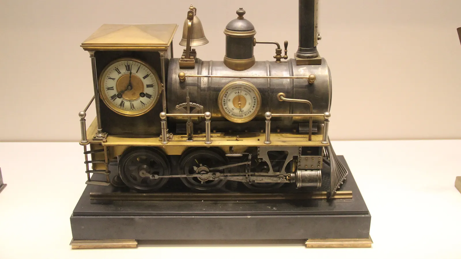 Horloge ancienne en laiton en forme de locomotive à vapeur, avec un cadran météo de très sec à orageux