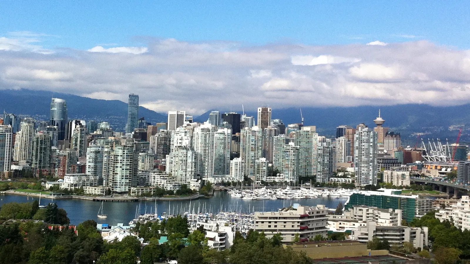 Horizon de Vancouver vu de l'autre côté de l'eau, avec des tours, un port rempli de bateaux et des montagnes en arrière-plan
